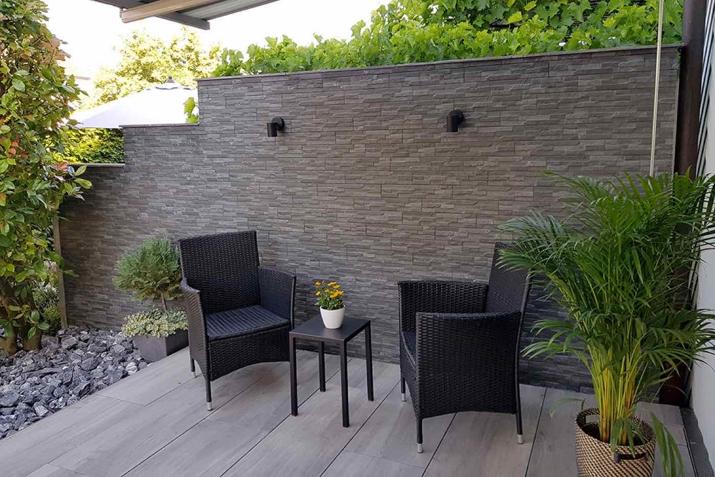 Terrasse mit Steinwand und Feinsteinzeug in Holzoptik